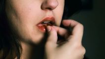Closeup of a woman placing a pill in her mouth.