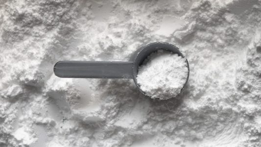 A scoop of white creatine powder.
