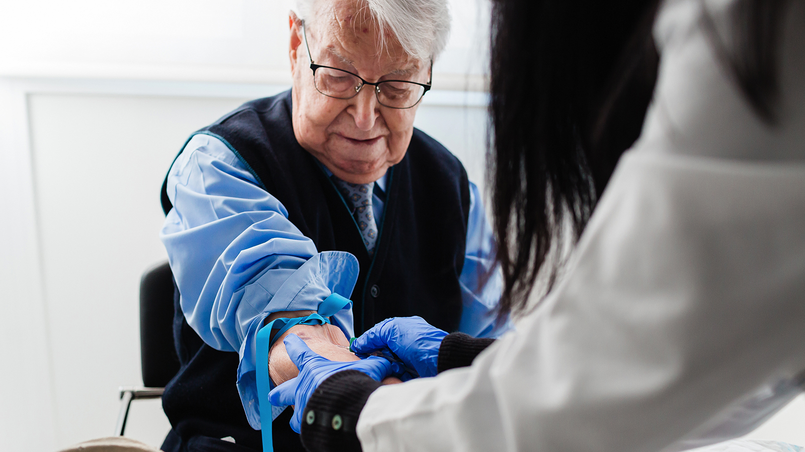 Nurse drawing blood from an elderly man
