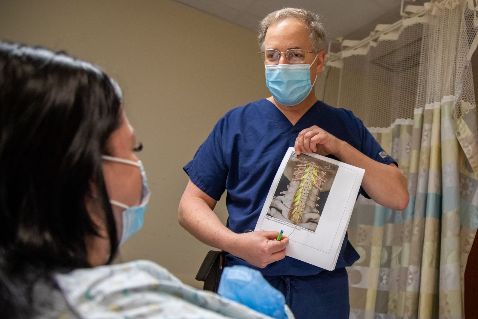 a surgeon showing a woman an image of where an implant will go in her neck 