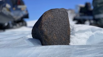 a large black rock in the snow
