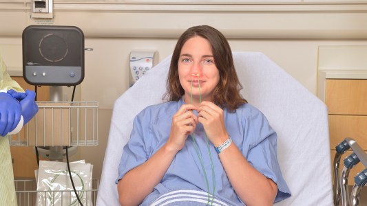 woman in hospital bed using nasal disinfecting device