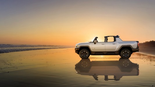 a vehicle on a beach with the sun behind it