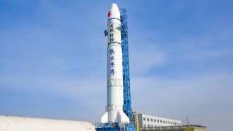 a tall rocket covered in Chinese writing on a launchpad