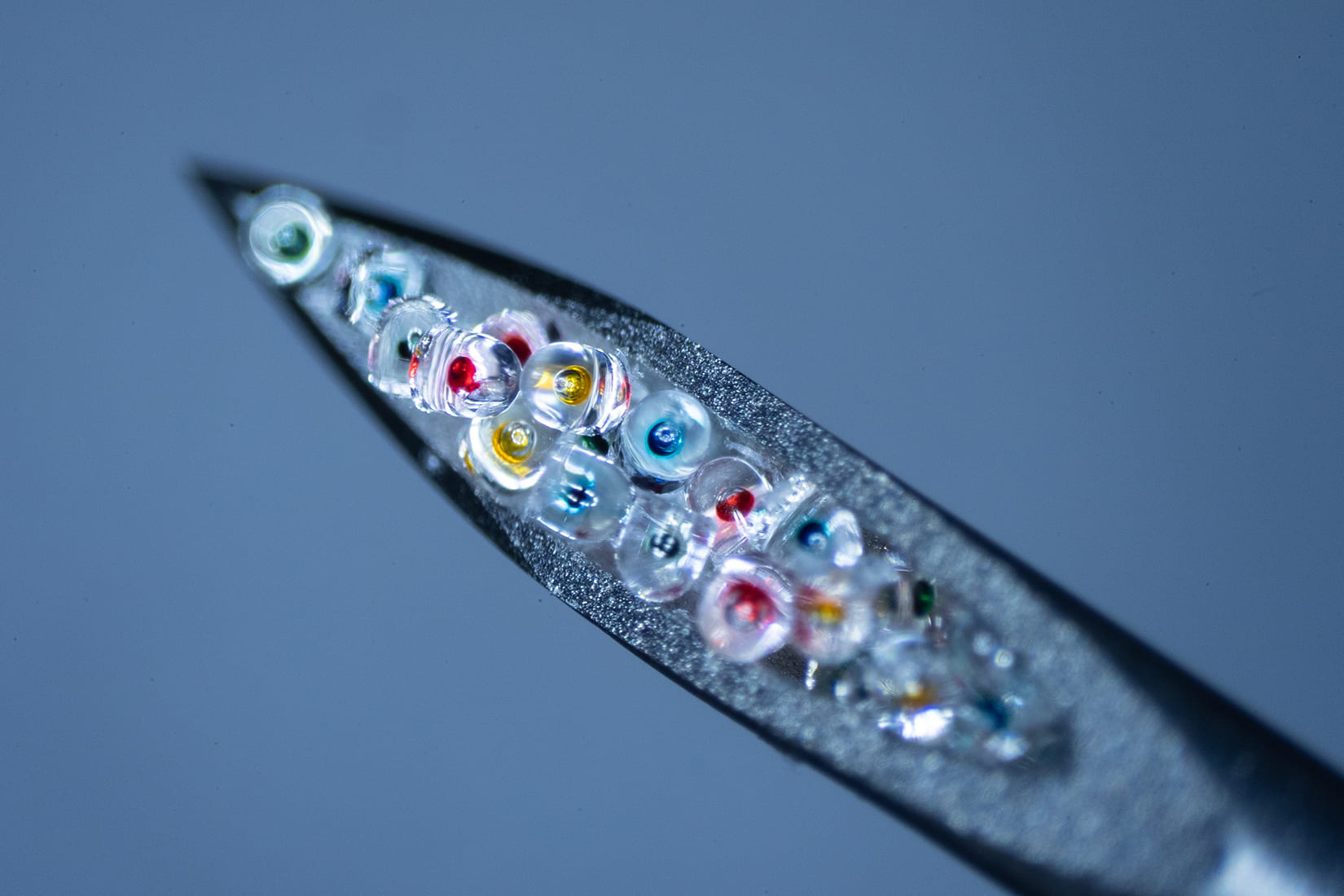 a close up of the end of a hypodermic needle filled with tiny colorful pellets