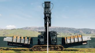 a large machine driving long steel beams deep into the ground