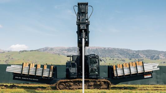 a large machine driving long steel beams deep into the ground