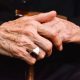A close-up of an elderly person's hands on a cane.