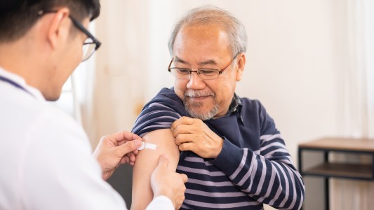 an older man receiving a vaccine in his arm