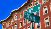 a street sign with "Harvard St" on it in front of a brick building