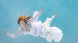 a woman in a white dress underwater.