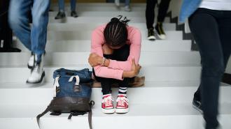 a girl with depression sitting on the stairs with her backpack.