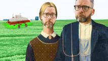 two men standing in a field with a tractor.