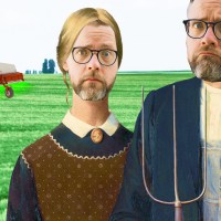 two men standing in a field with a tractor.