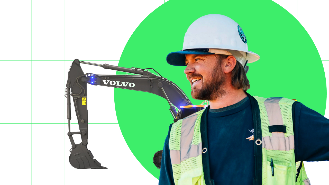 A man in a hard hat is standing next to an excavator.