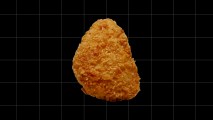 A piece of lab-grown fried chicken on a black background.