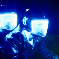 Two men wearing helmets with blue lights on them on a ride.