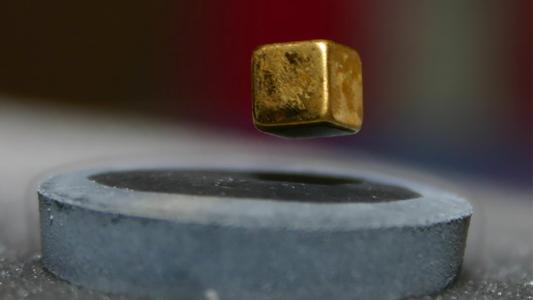 a cube of metal floating above a magnet