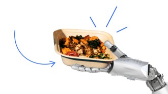 A robot hand is holding a container of food.
