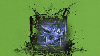 A glass of water with a green splash on a blue background.