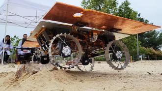 A model rover driving over a rock