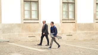 A man and a woman walking down a cobblestone street.