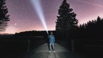 A person standing on a dock with a flashlight.