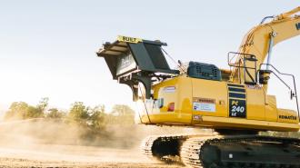 A yellow excavator on a dirt field.