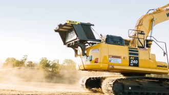 A yellow excavator on a dirt field.