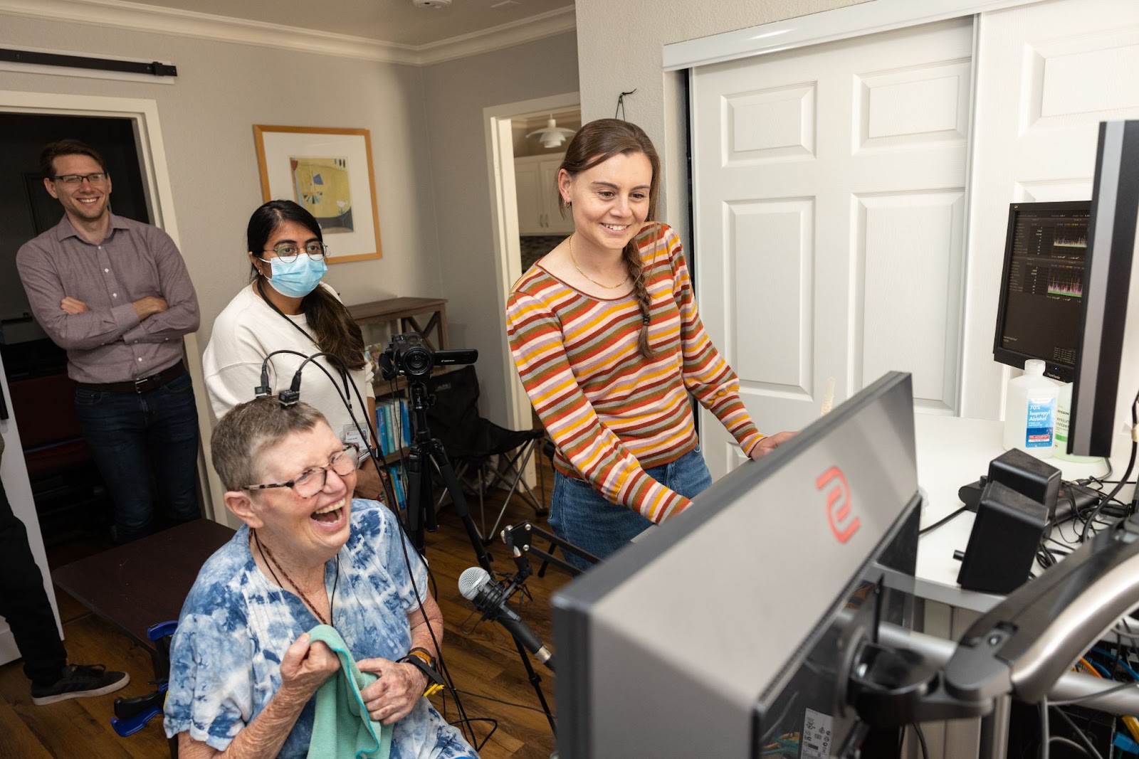 Pat Bennett and several members of the research team looking at a computer screen while she uses the speech bci