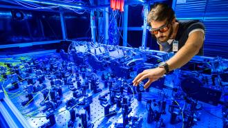 A man is working on a muon g-2 machine in a blue room.