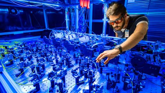 A man is working on a muon g-2 machine in a blue room.