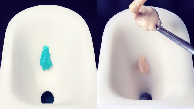 A spoon is being used to scoop synthetic feces into a tiny toilet bowl.