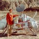 A man exploring life on Mars standing next to a spacecraft in the desert.