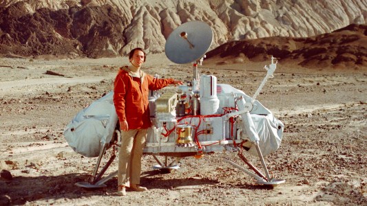 A man exploring life on Mars standing next to a spacecraft in the desert.