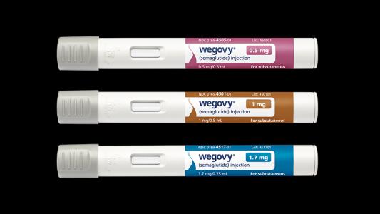 Three tubes of wypy, a weight-loss drug, on a black background.