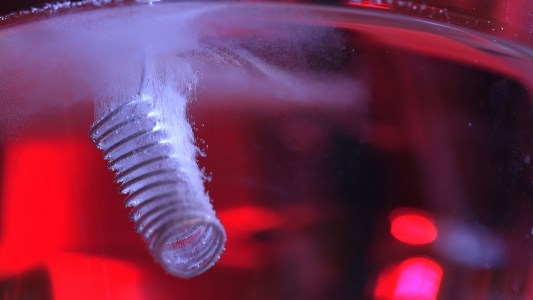 a spring-like electrode covered in bubbles inside a liquid