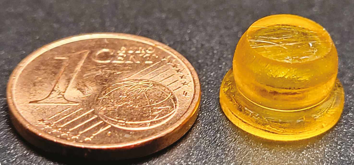 A coin next to a tiny orange suction cup