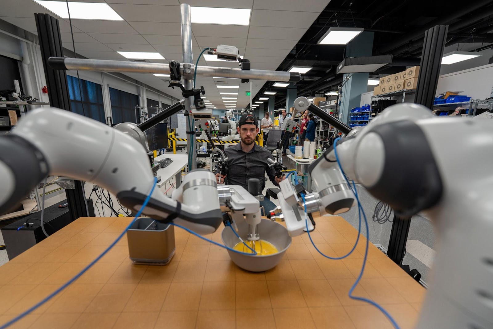 A TRI researcher using the teleoperation interface to teach a robot to beat eggs