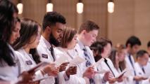A group of people in white coats pursuing a dual degree in medicine and AI standing in a line.
