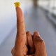 A person's finger is holding up a small yellow suction cup