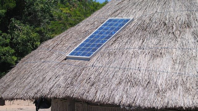 A solar panel on the roof of a hut.