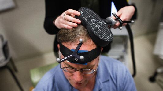 Research assistant Gabrielle Block simulates a TMS therapy session on John Elder Robison as he sits in the room where he took part in brain therapy known as TMS (Transcranial magnetic stimulation) at Beth Israel Hospital in Boston, Mass., March 15, 2016.