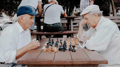 Two elderly men sitting at a table playing chess