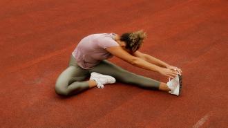 A woman stretching on a red field.