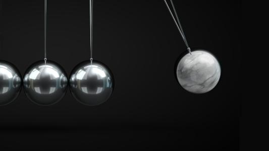 Three silver balls hanging on a black background.