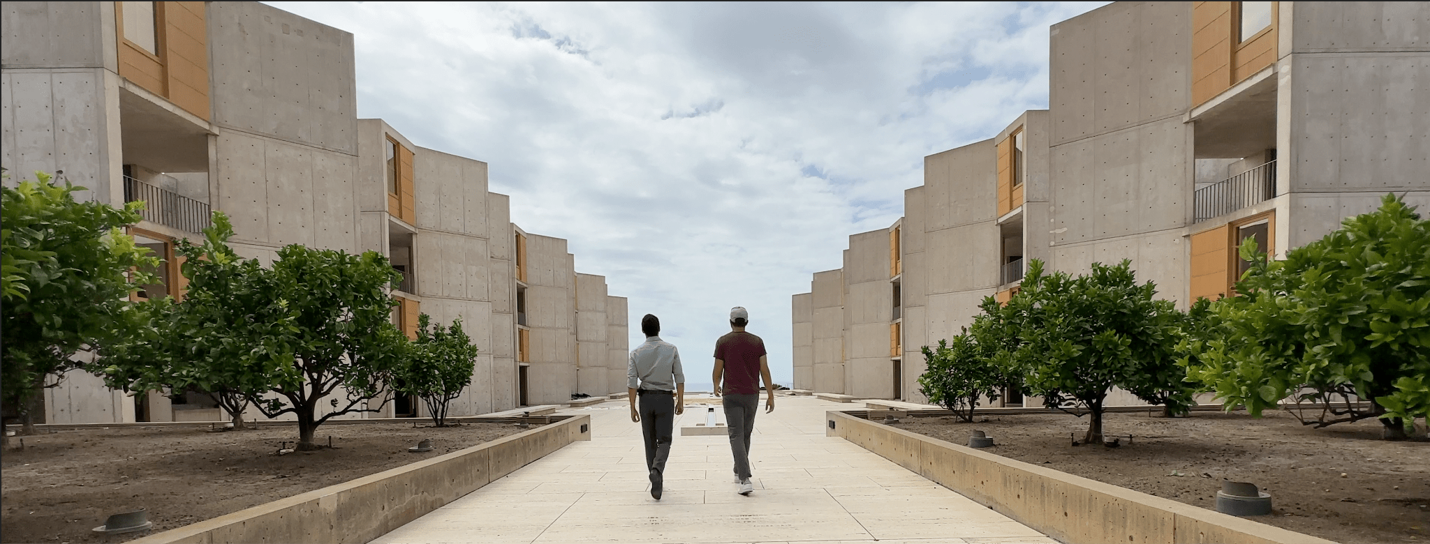 Two people walking down a path in front of a building.