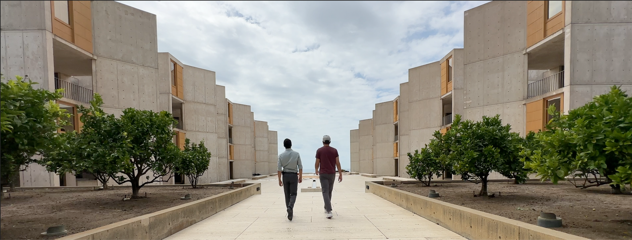 Two people walking down a path in front of a building.