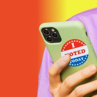 A person holding a cell phone with a sticker that says i voted.