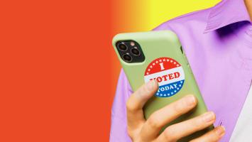 A person holding a cell phone with a sticker that says i voted.